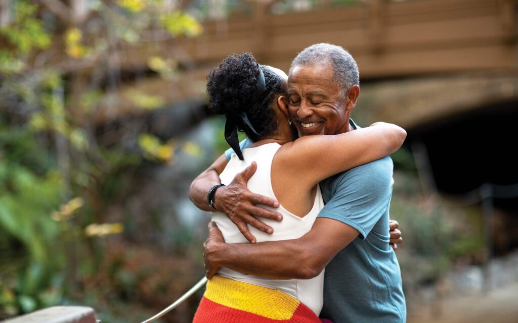 A man hugging his spouse infront of their home