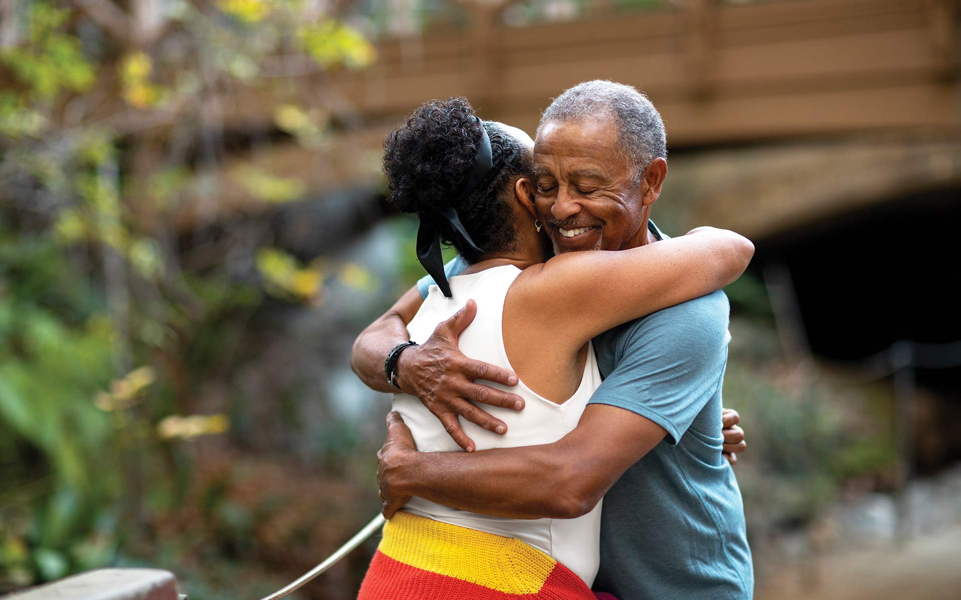 A man hugging his spouse infront of their home